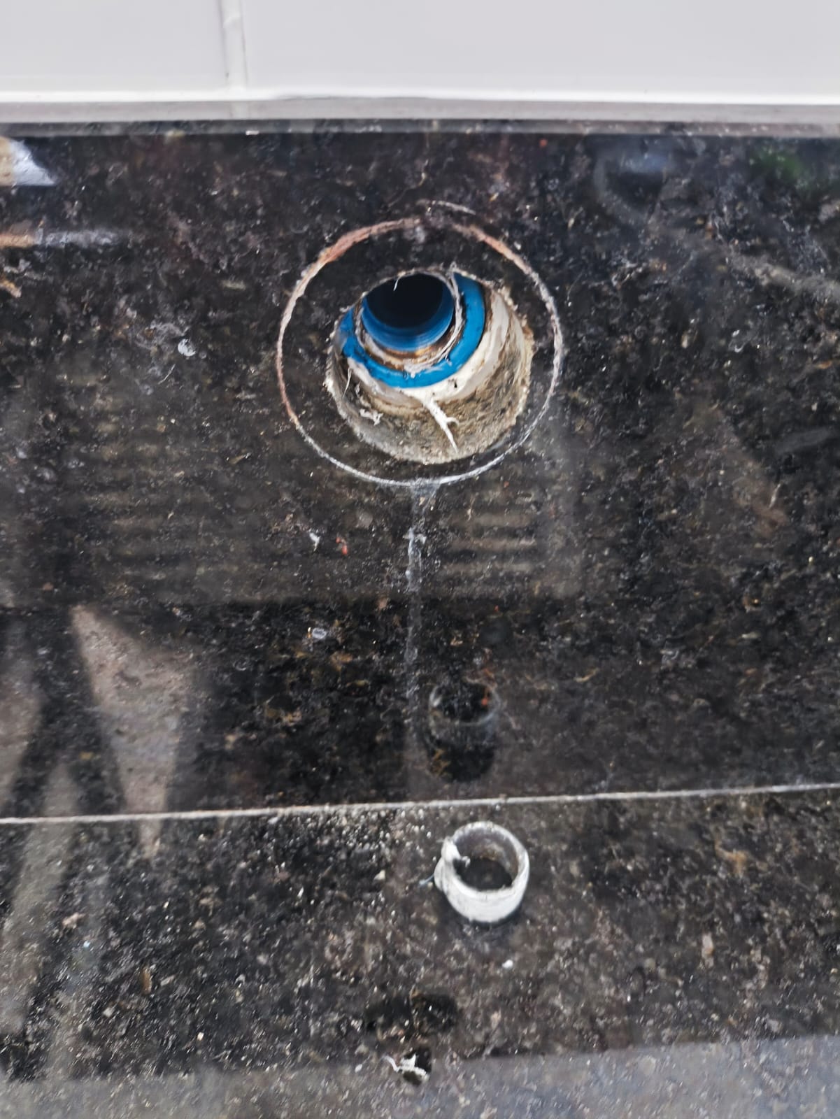 Conexão hidráulica danificada em bancada de granito, antes do reparo